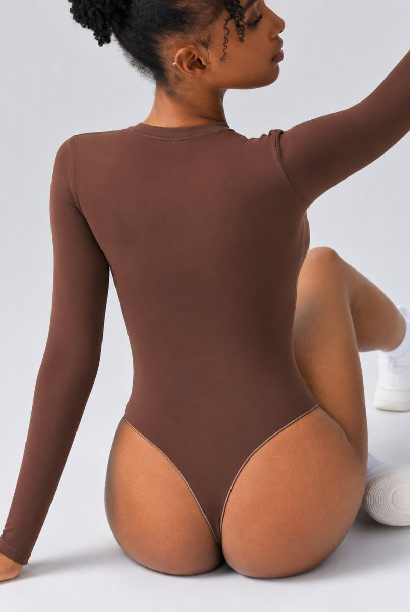 Woman wearing Aether Sculpting Long Sleeve Bodysuit in coffee, shown in a seated back pose with a sculpting fit.