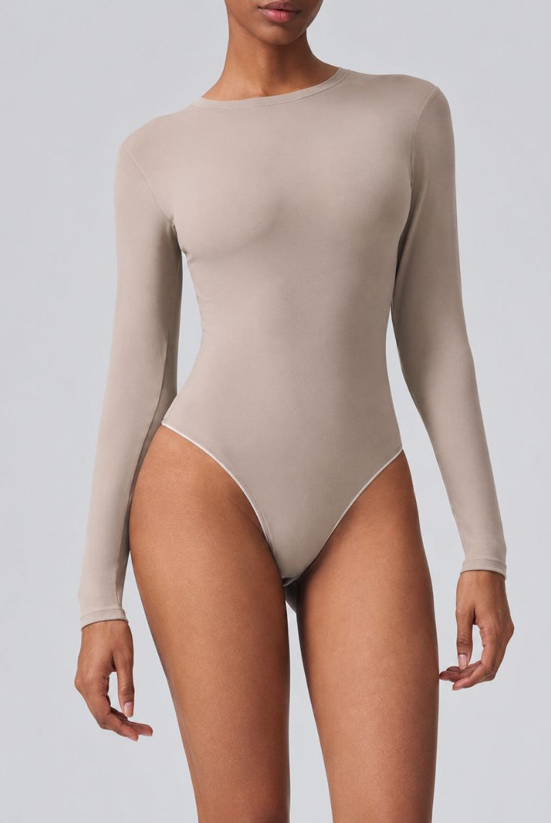 Woman wearing Aether Sculpting Long Sleeve Bodysuit in khaki, shown in a front pose with a sculpting fit.