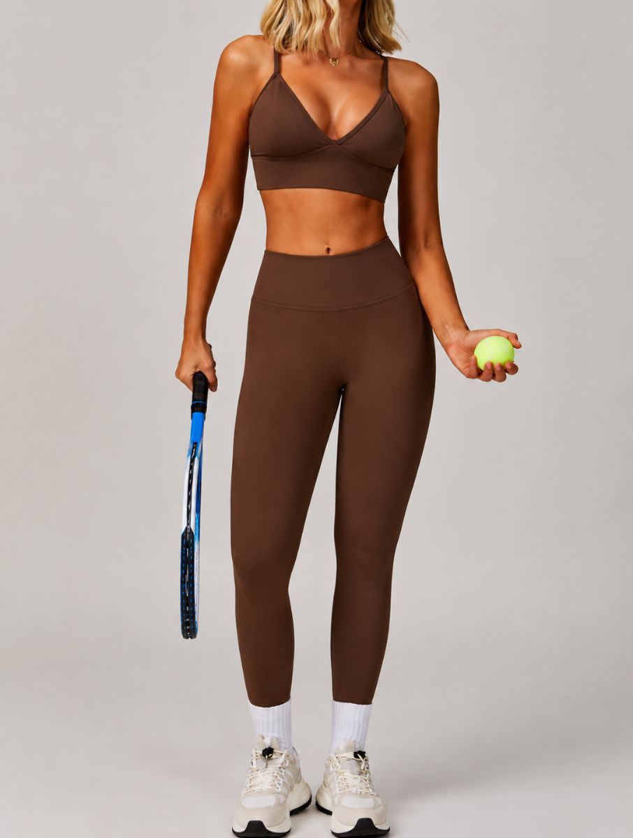 Woman wearing the ContourFlex Seamless Top & Leggings in Dark Coffee, standing in a front-facing tennis pose while holding a racket and ball.