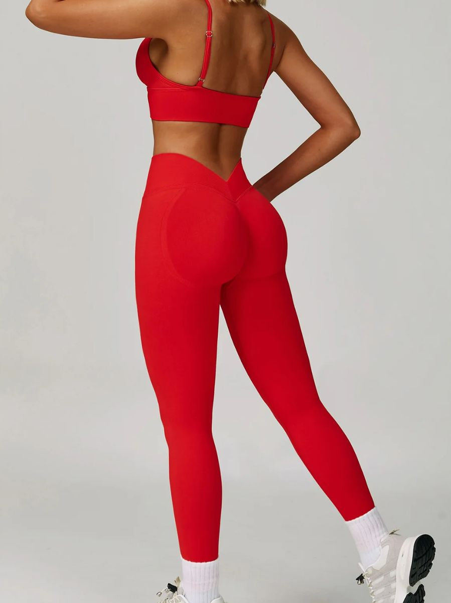 Woman wearing the ContourFlex Seamless Top & Leggings in Red, posing from the back with one hand on her hip and one leg slightly raised.
