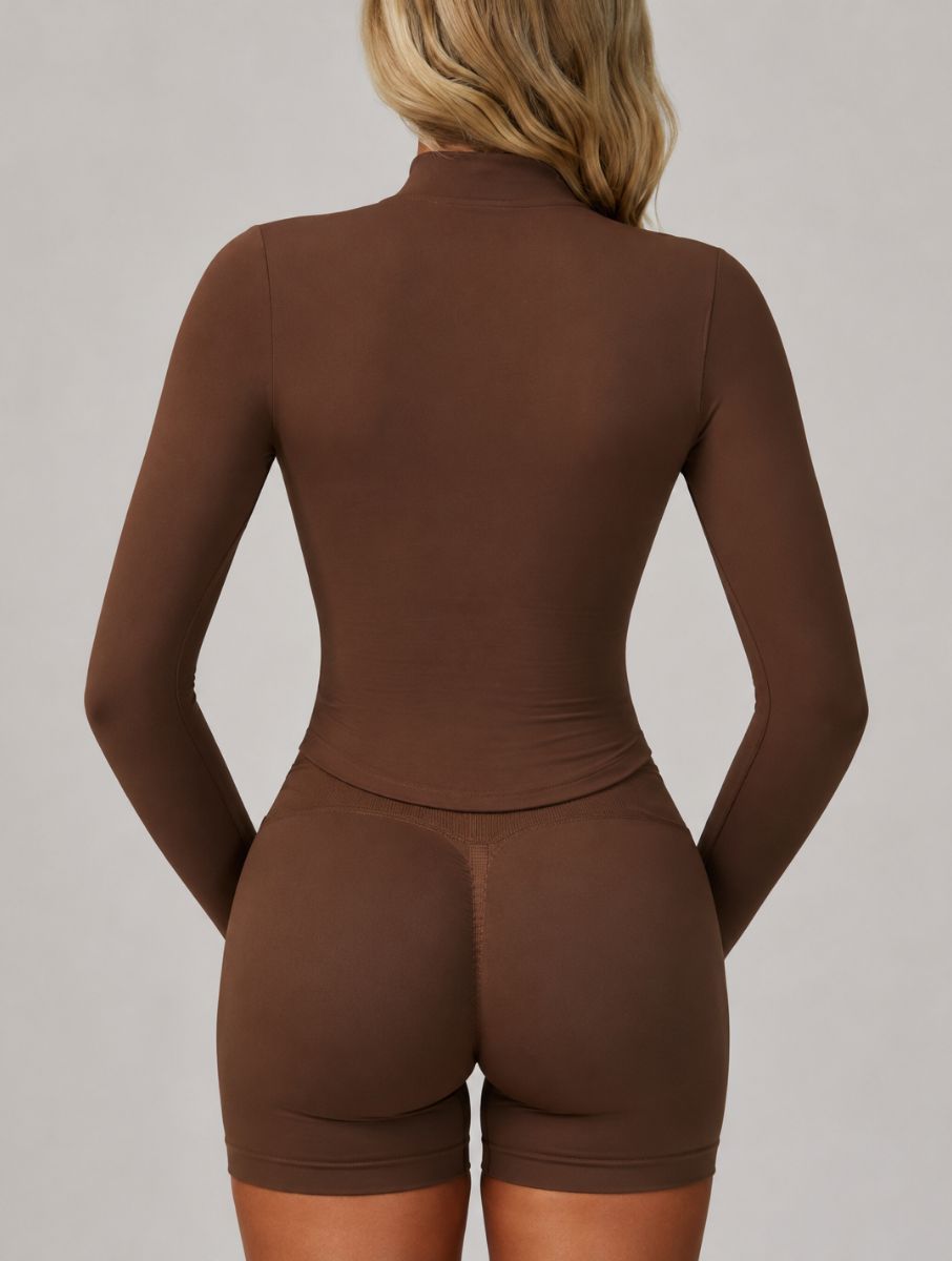 Back view of a woman wearing the ContourFlex Three-Piece Set in dark coffee, featuring a fitted jacket and shorts, standing with her hands behind her back.