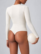 Woman wearing Aether Sculpting Long Sleeve Bodysuit in white, shown in a back pose with a sculpting fit.