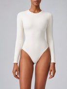 Woman wearing Aether Sculpting Long Sleeve Bodysuit in white, shown in a front pose with a sculpting fit.