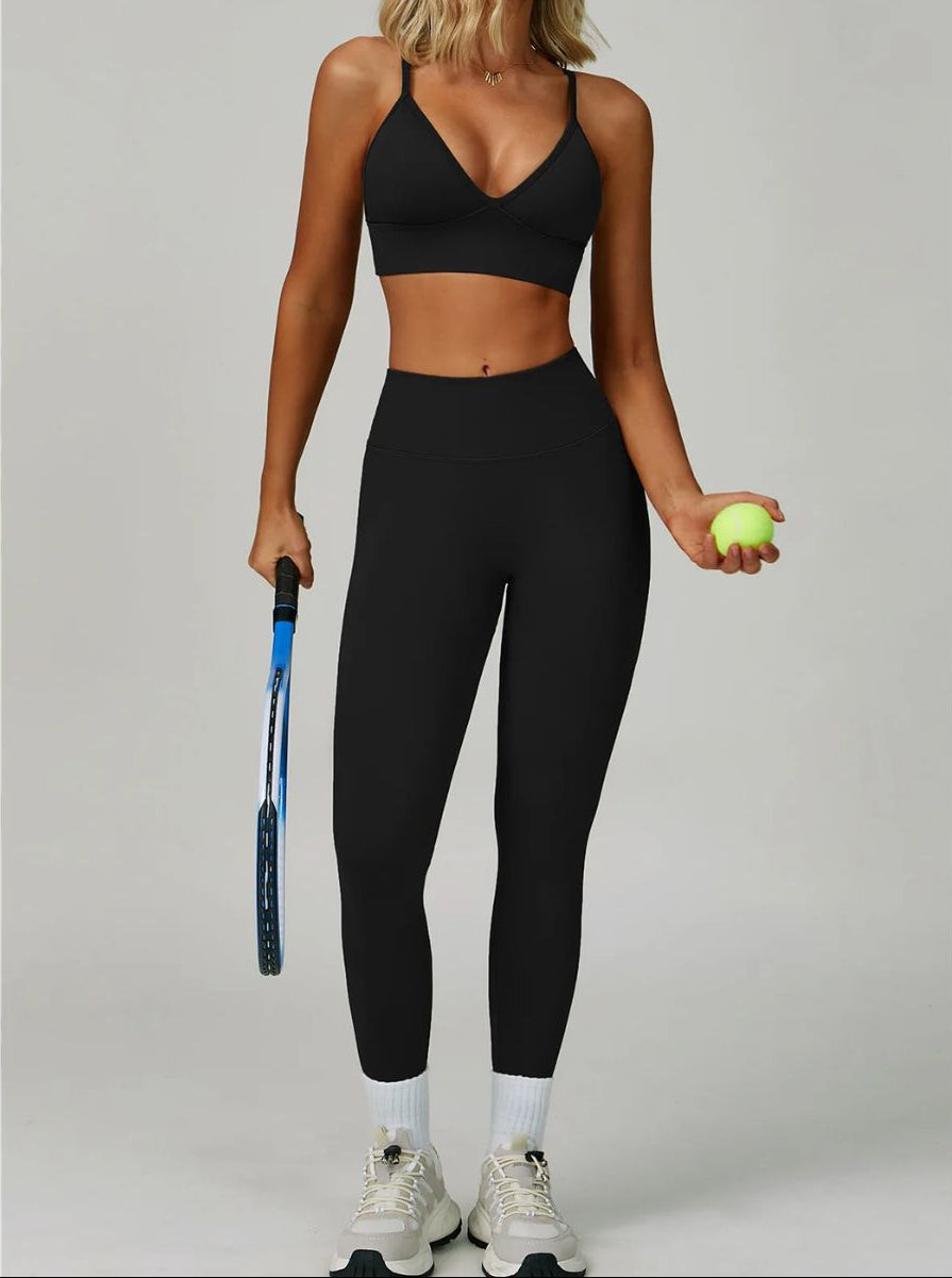 Woman wearing the ContourFlex Seamless Top & Leggings in Black, standing in a front-facing tennis pose while holding a racket and ball.