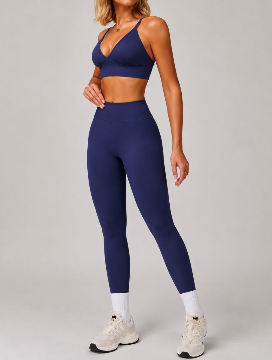 Woman wearing the ContourFlex Seamless Top & Leggings in Navy Blue, standing in a three-quarter pose with one hand resting near her waist.