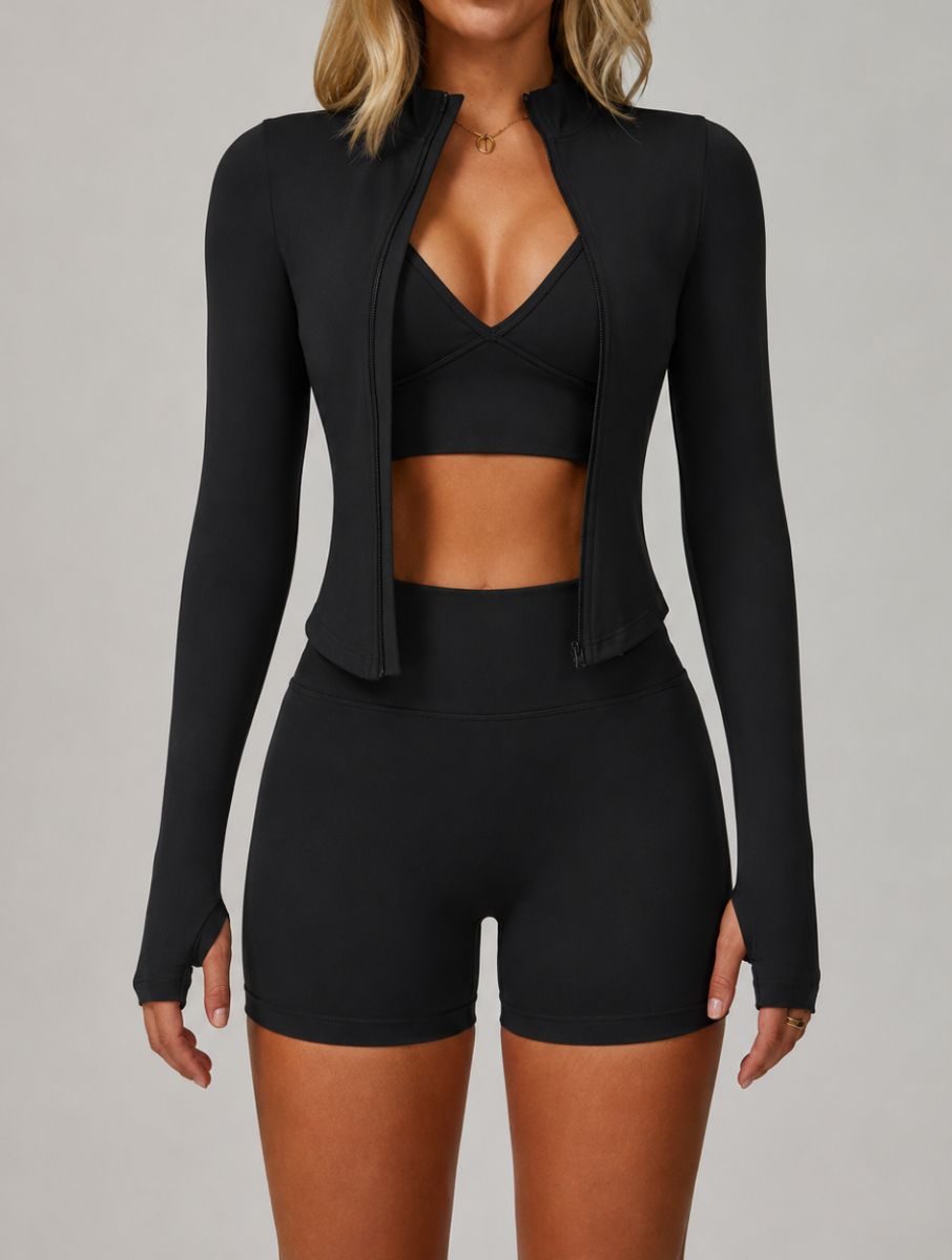 Front view of a woman wearing the ContourFlex Three-Piece Set in black, featuring a sports bra, fitted jacket, and shorts, standing with her arms at her sides.