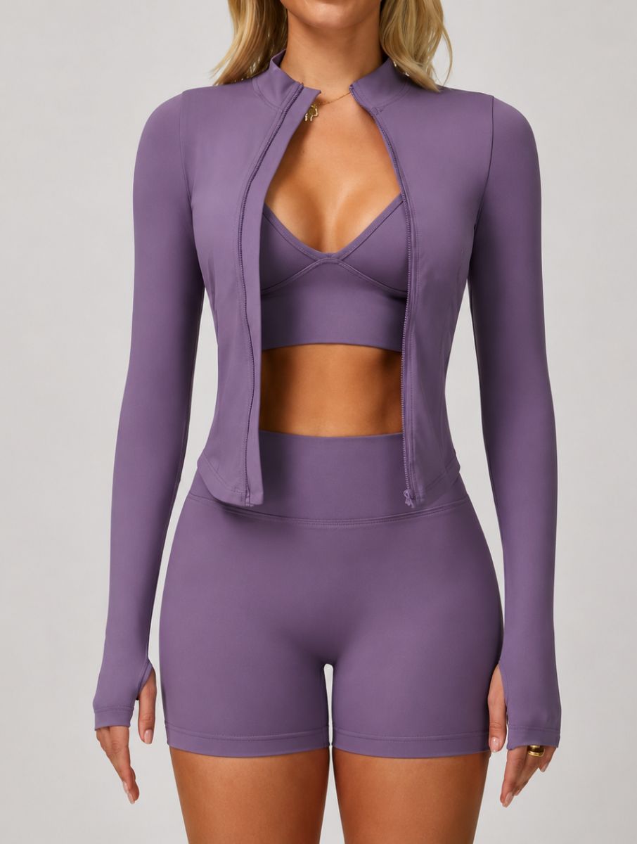 Front view of a woman wearing the ContourFlex Three-Piece Set in purple, featuring a sports bra, fitted jacket, and shorts, standing with her arms at her sides.