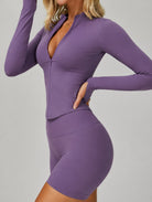 Side view of a woman wearing the ContourFlex Three-Piece Set in purple, featuring a fitted jacket and shorts, posing with one hand on her hip.