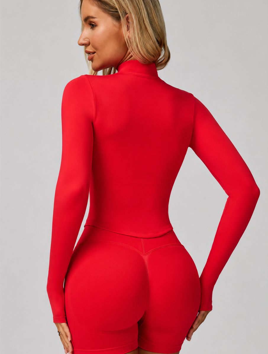 Back view of a woman wearing the ContourFlex Three-Piece Set in red, featuring a fitted jacket and shorts, posing with her hands by her sides while looking over her shoulder.