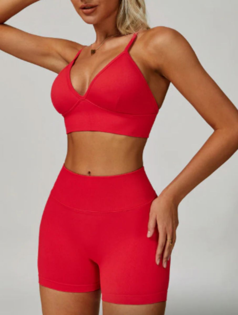 Woman wearing the ContourFlex Seamless Top & Shorts in Red, posing in a front-angle stance with one arm raised.